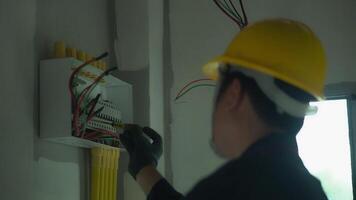 A Electrician using electric screwdriver tester to check electric current in control box in home electrical installation and safety concept video