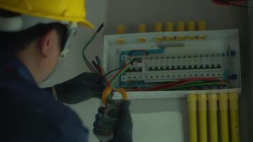 Close-up of electrician using tools to check electrical wiring in home control box. video