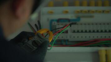 Close-up of electrician using tools to check electrical wiring in home control box. video