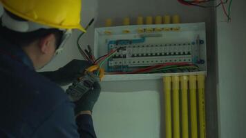A electrician using tools to check electrical wiring in home control box. video