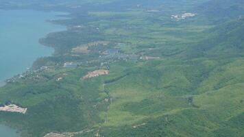 aerial view over green field tropical climate forest area while flying on airplane above puffy cloud level in sunny day video