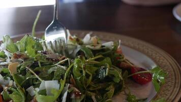 usinng fork and knife to eat mediterranean salad food topped with almond and cheese sliced in home cooking style for appetizer in dinner time video