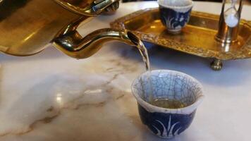 view to a cup of tea while pouring tea from tea pot in chinese japanese modern golden design on marble table video