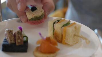 close up selective focus to canape sandwich in white plate while using hand to grab canape to eat in afternoon tea time video