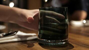close up view to a glass of fresh mineral water on the wooden table while using hand grab a glass to drink and place on a table video