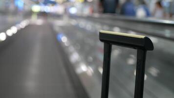 pov with selective focusing to luggage handle handheld on the moving escalator walkway while in airport departure terminal hall moving to departure gate video