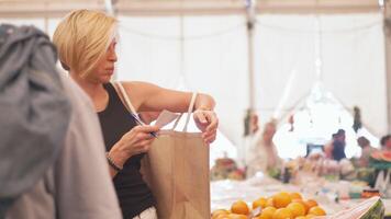 Woman ticking grocery checklist while shopping in market during daytime video