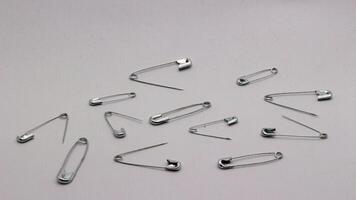 The safety pin is made of metal and silver in color. photo