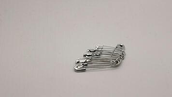 The safety pin is made of metal and silver in color. photo