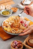 Emie, mie rebus is a noodle soup made from broth shrimp, topping boiled egg and potato, dried shrimp, fried onion and onion leaf. photo