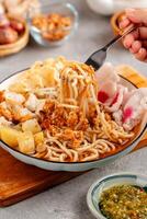 Emie, mie rebus is a noodle soup made from broth shrimp, topping boiled egg and potato, dried shrimp, fried onion and onion leaf. photo