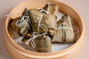 Zongzi is a traditional Chinese food made of glutinous rice stuffed with different fillings and wrapped in bamboo reed, or other large flat leaves. They are cooked by steaming or boiling. photo