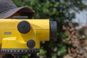 cap of an archaeologist behind a theodolite in an archaeological excavation. Measure tools photo
