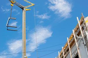 partial view of the attic of a house under construction and crane in a blue sky day. photo