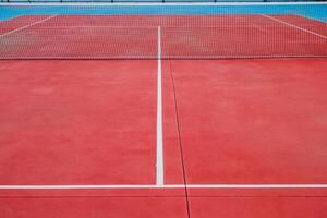 view of the net of an empty red tennis court photo