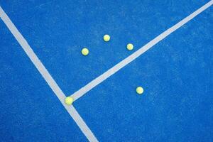 Top view of a line and texture of blue paddle tennis court and five yellow balls. Artificial grass paddle court surface. photo