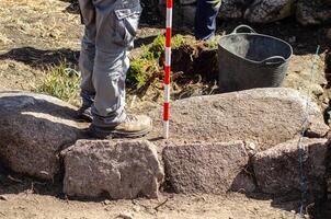 view of the legs of an archaeologist holding a range pole in an archaeological excavation. Archeology concept photo