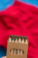 box of colored pencils with red and blue out of focus background, back to school photo