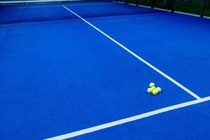 balls on an empty paddle tennis court in the night photo