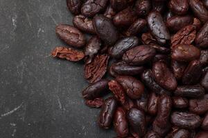 Cocoa beans on black table background photo