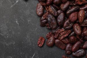 Cocoa beans on black table background photo