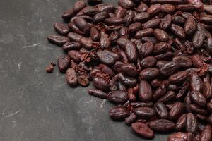 Cocoa beans on black table background photo