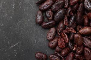 Cocoa beans on black table background photo