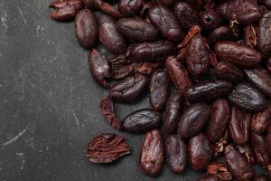 Cocoa beans on black table background photo