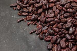 Cocoa beans on black table background photo