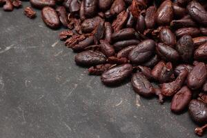 Cocoa beans on black table background photo
