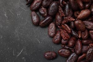 Cocoa beans on black table background photo