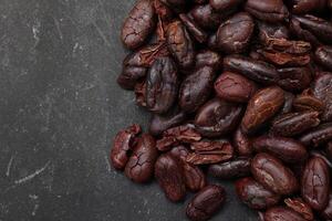 Cocoa beans on black table background photo