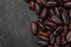 Cocoa beans on black table background photo