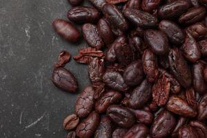 Cocoa beans on black table background photo