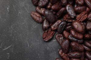 Cocoa beans on black table background photo