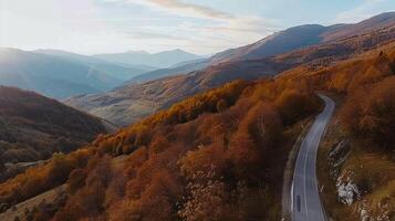 devanado la carretera mediante otoño bosque en el montañas a puesta de sol foto