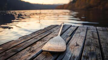 Wooden Oar on a Lakeside Dock at Sunset with Scenic Background photo