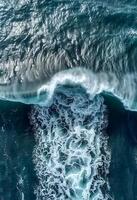Aerial view of ocean waves crashing on a sandy beach photo