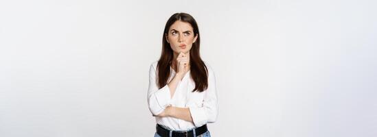 Portrait of female entrepreneur thinking, making choice, standing thoughtful, white studio background photo