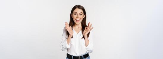 Enthusiastic laughing woman, smiling amused, clapping hands, applausing, standing in formal outfit over white background photo