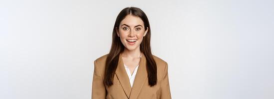 Portrait of business woman with enthusiastic face expression, smiling, looking confident, standing in suit over white background photo