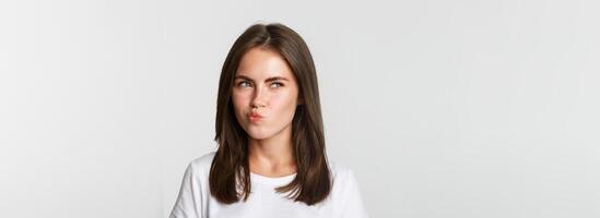 Close-up of thoughtful pretty girl looking upper left corner doubtful, thinking over white background photo