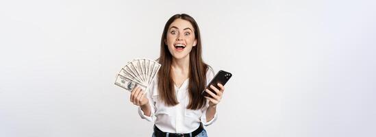 en línea microcrédito préstamos y bancario concepto. contento mujer participación móvil teléfono y dinero, sonriente y reír, en pie terminado blanco antecedentes foto