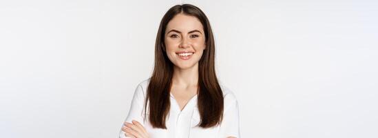 Close up of confident corporate woman, professional entrepreneur smiling, cross arms on chest and smiling enthusiastic, standing over white background photo