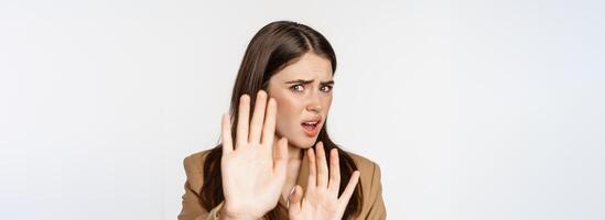 Close up portrait of disgusted, shocked woman cringe, turn away and blocking from something disgusting, standing against white background photo