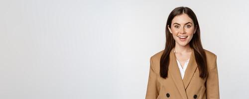 Portrait of business woman with enthusiastic face expression, smiling, looking confident, standing in suit over white background photo