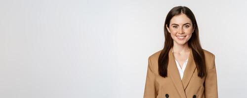 Portrait of business woman with enthusiastic face expression, smiling, looking confident, standing in suit over white background photo