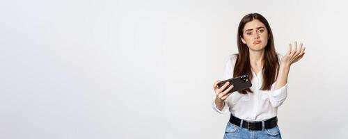 Sad woman losing in mobile game, looking upset and disappointed at smartphone, sulking, standing over white background photo