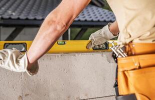 Construction Worker Using Level Tool on Block Wall at Job Site photo