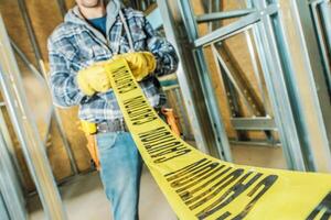Construction Worker Handling Caution Tape at a Building Site During Daylight photo
